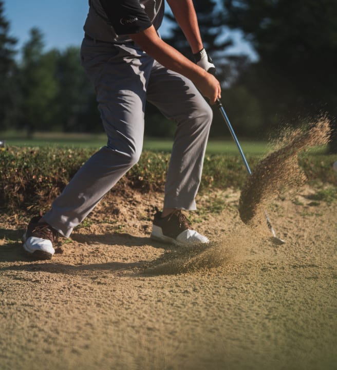 Man hitting a gold ball on a golf course