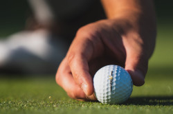 Person positioning a golf ball