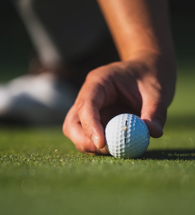Person positioning a golf ball