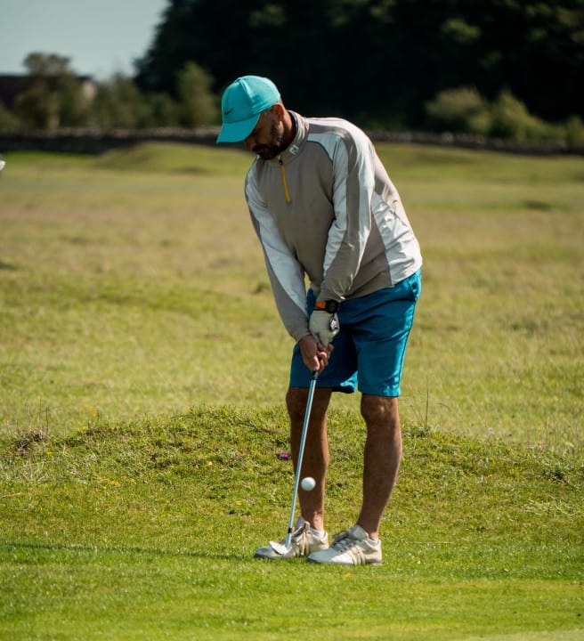 A person hitting a gold ball