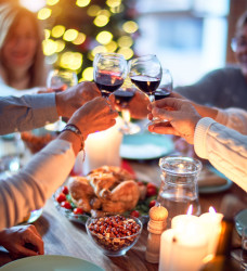 People clinking glasses together over Christmas dinner