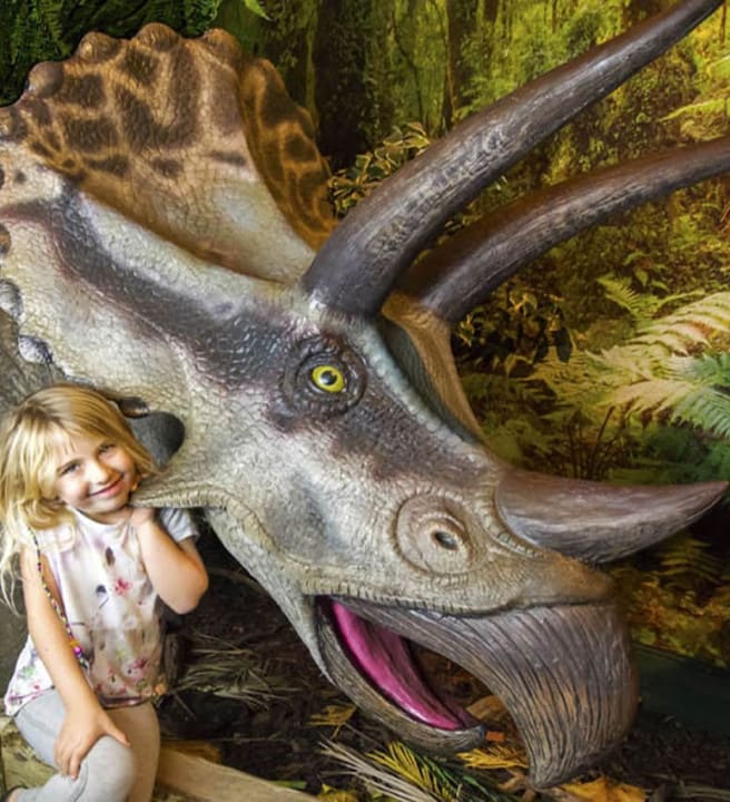 Child posing with a life sized dinosaur