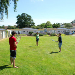 People playing tennis on the green at Hazelwood Holiday Park