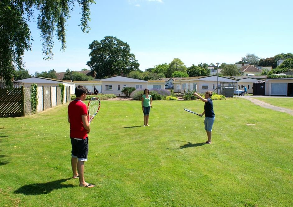 People playing tennis on the green at Hazelwood Holiday Park