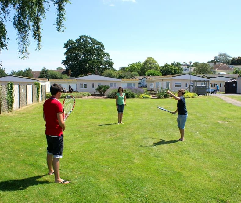 People playing tennis on the green at Hazelwood Holiday Park