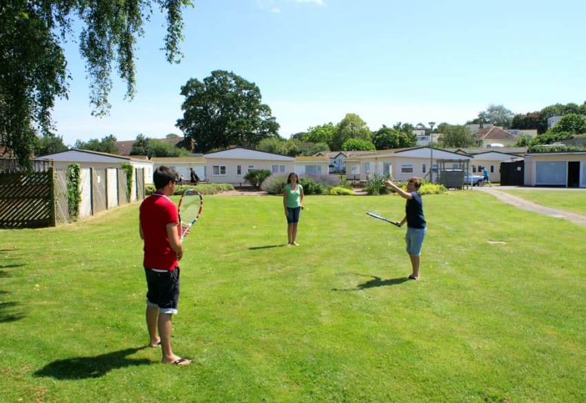 People playing tennis on the green at Hazelwood Holiday Park