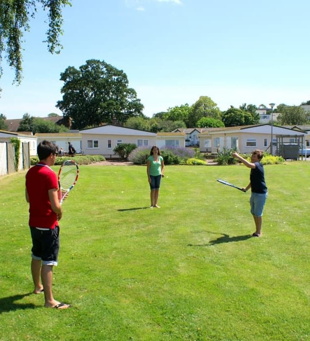 People playing tennis on the green at Hazelwood Holiday Park