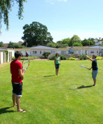 People playing tennis on the green at Hazelwood Holiday Park