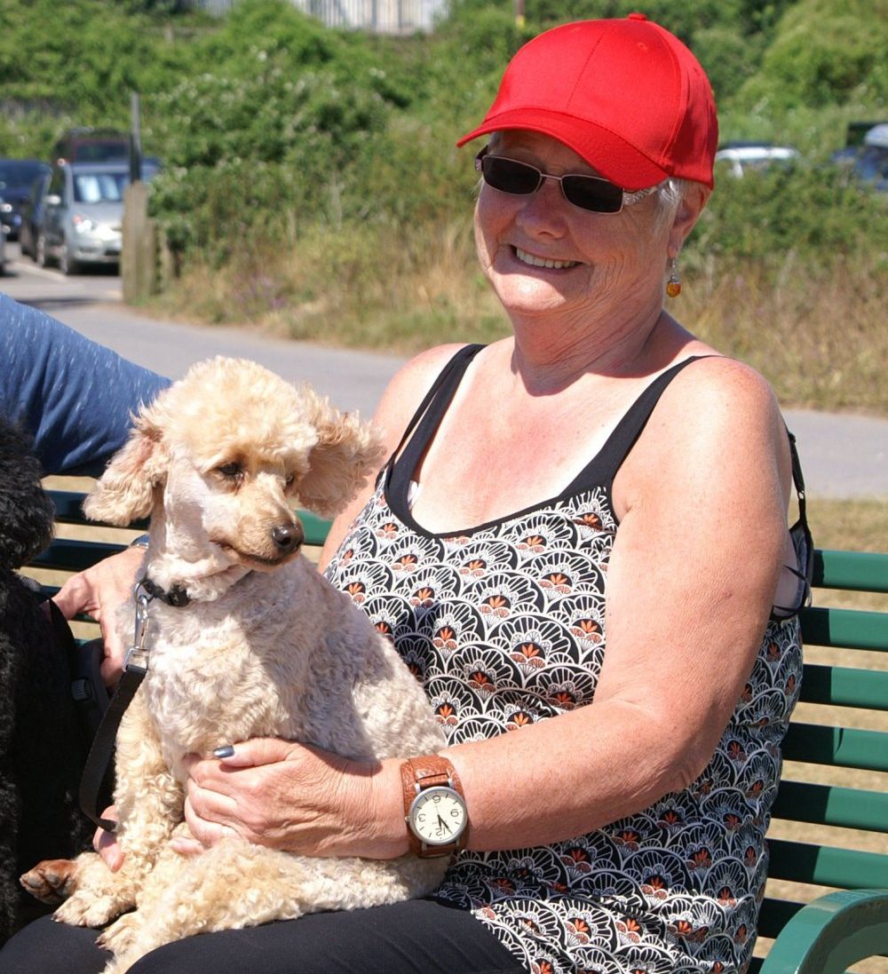 lady with a dog sitting on a bench in the sun