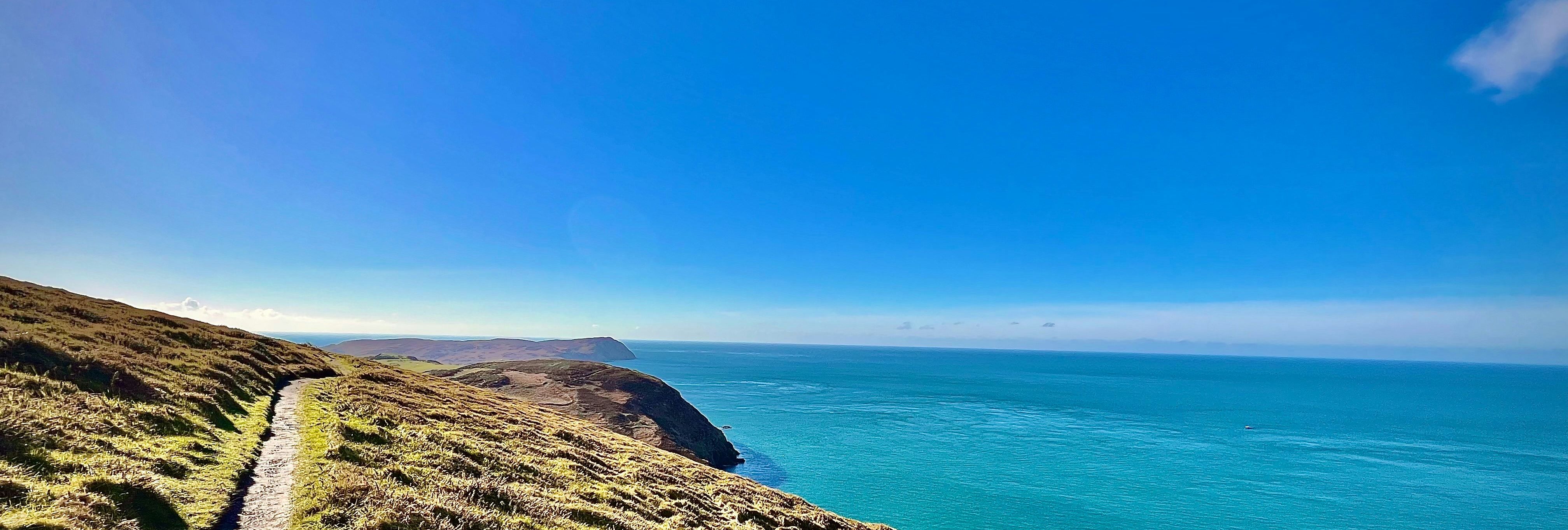 Coastal hiking trail overlooking a vast blue sea under a clear sky