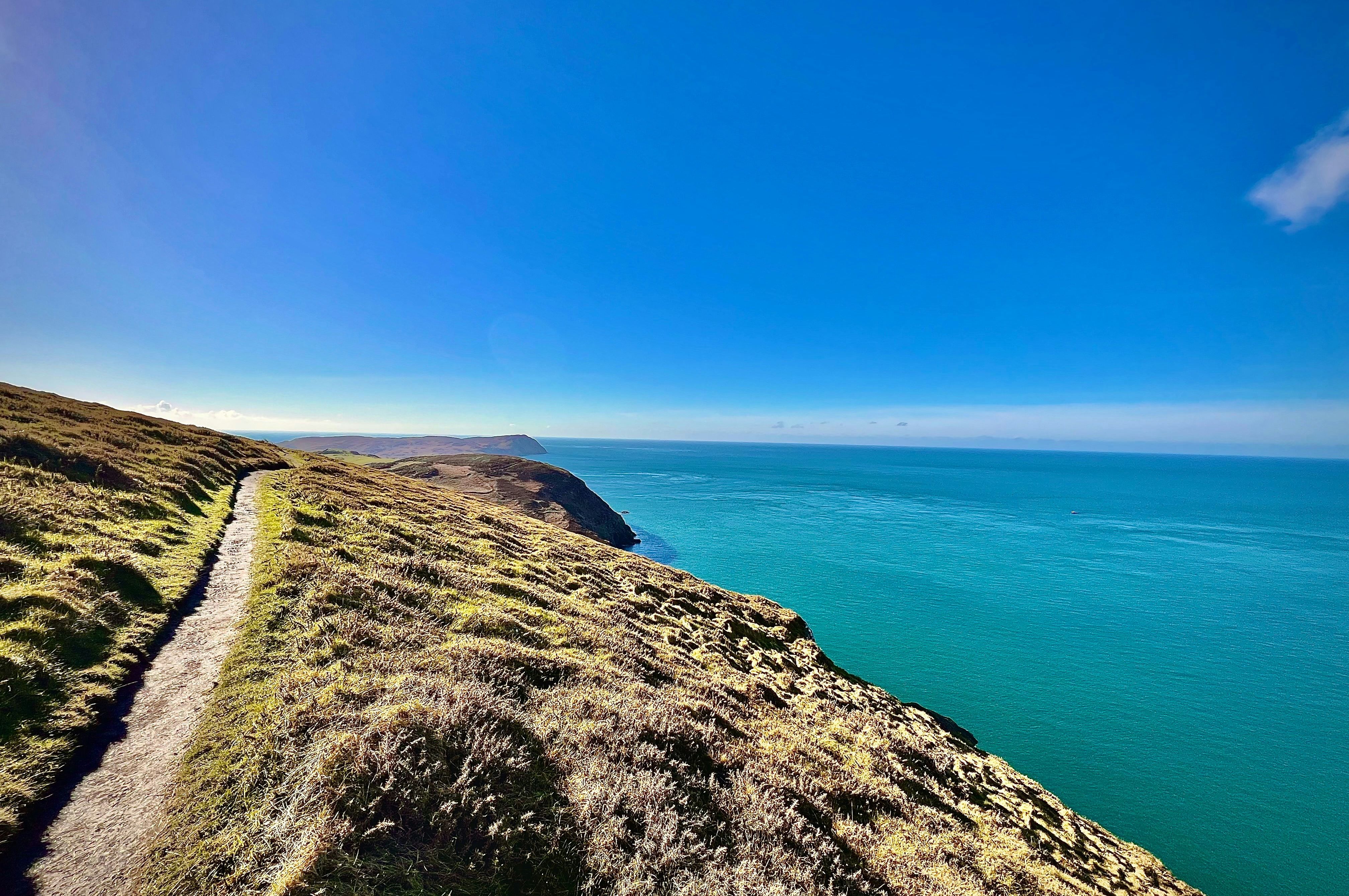 Coastal hiking trail overlooking a vast blue sea under a clear sky