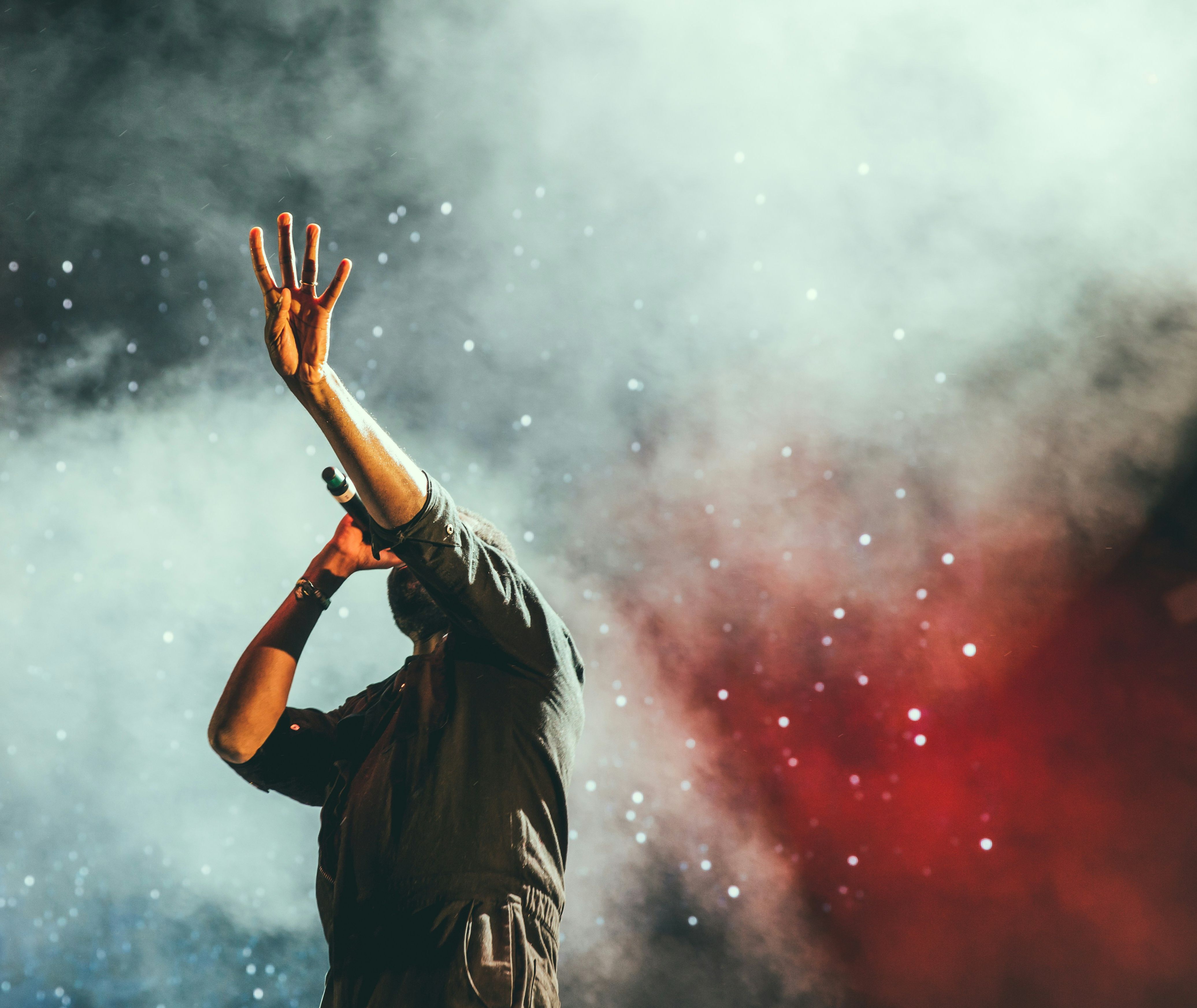 Singer on stage performing under dramatic lighting and smoke effects