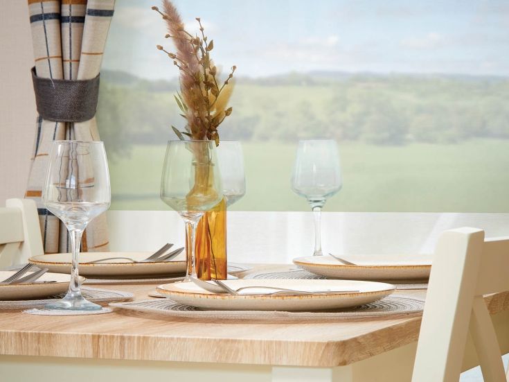 Willow classic dining table set with plates and wine glasses by a window