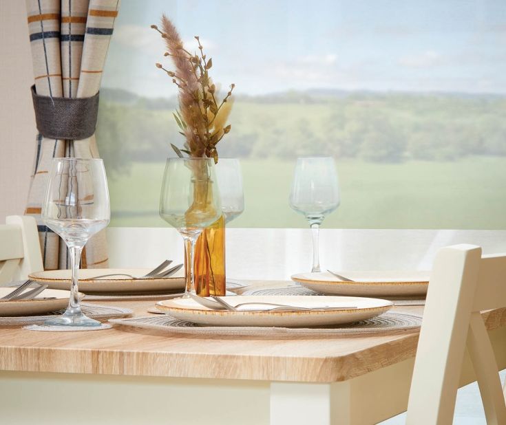 Willow classic dining table set with plates and wine glasses by a window