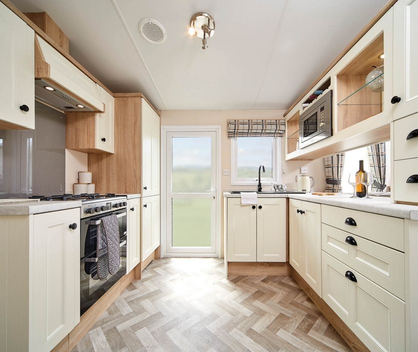 Classic galley kitchen with cream cabinets, wood trim and herringbone vinyl flooring