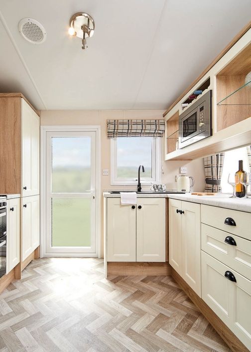 Classic galley kitchen with cream cabinets, wood trim and herringbone vinyl flooring