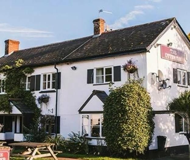 Traditional white-painted countryside pub with black shutters and hanging baskets