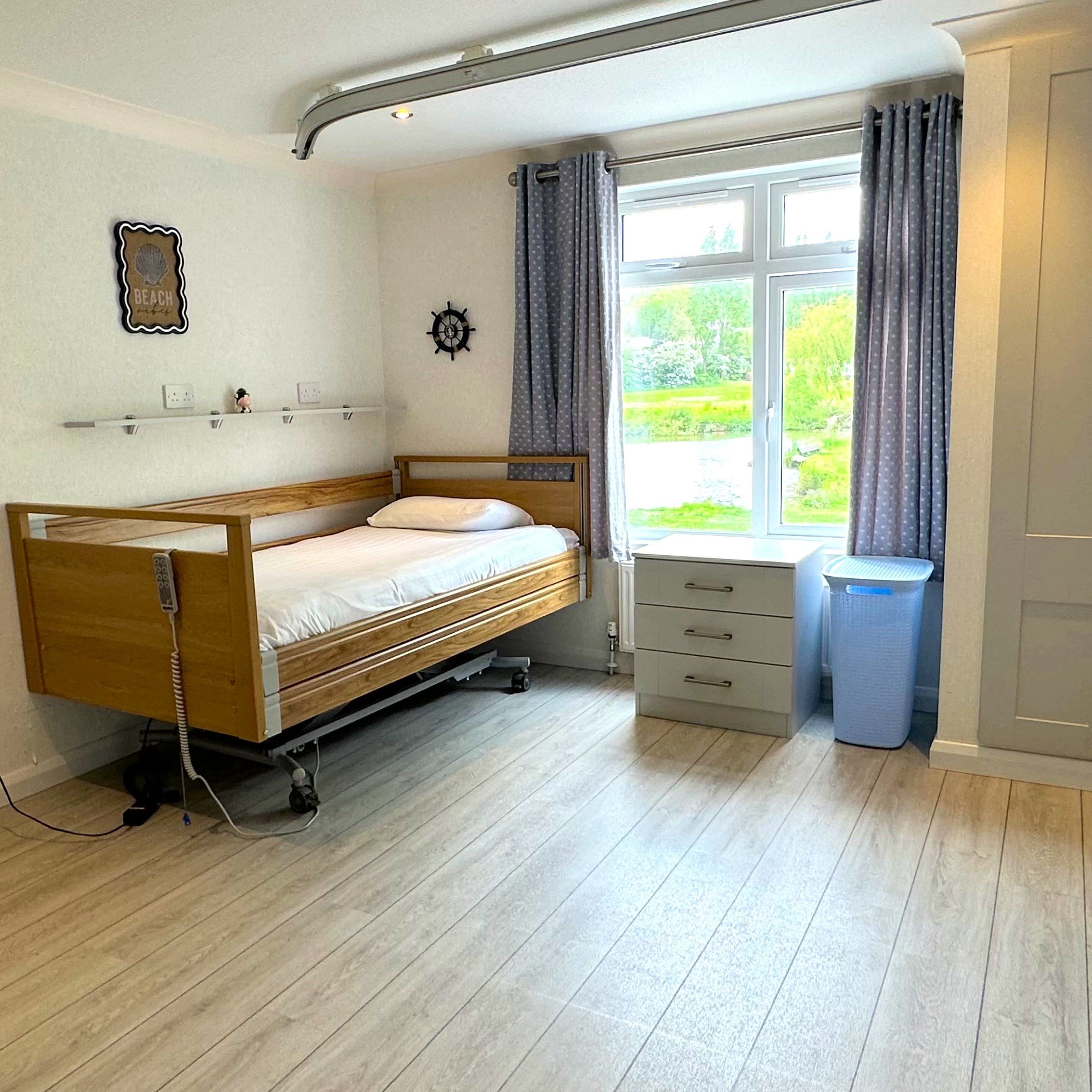 Large bedroom with an adjustable electric bed, fitted wardrobes and window with grey curtains at Maplewood Liberty