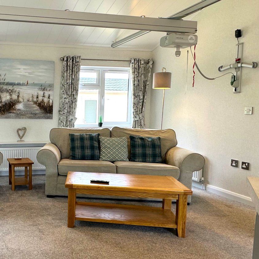 Bright living area with two sofas, wooden coffee table and large windows with patterned curtains in Maplewood Liberty 1500