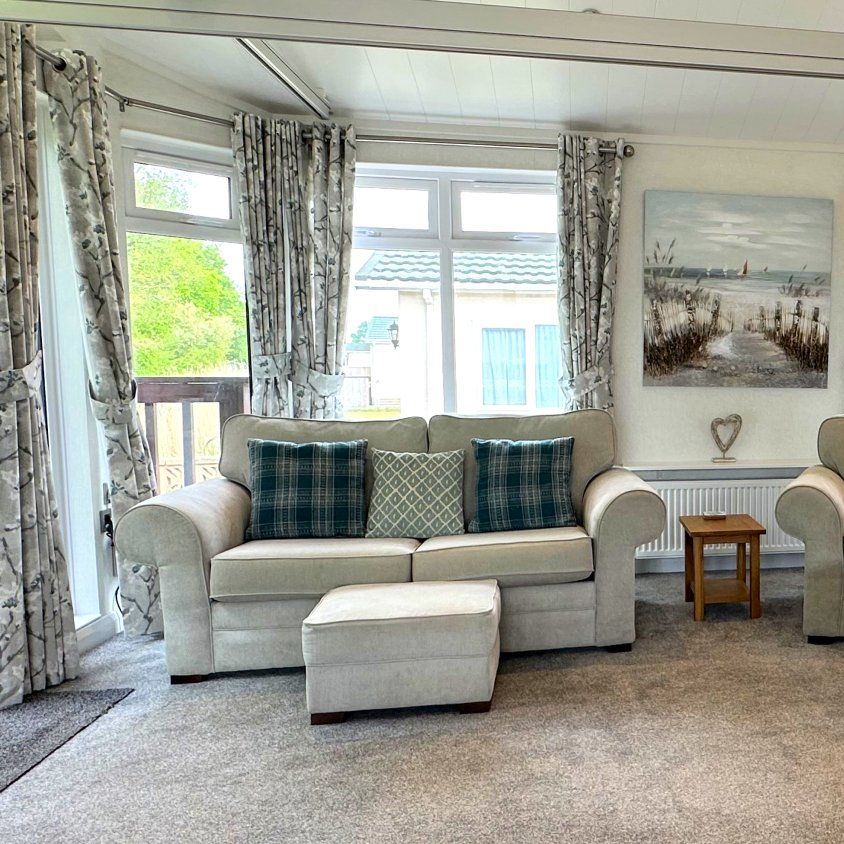 Bright living area with two sofas, wooden coffee table and large windows with patterned curtains in Maplewood Liberty 1500
