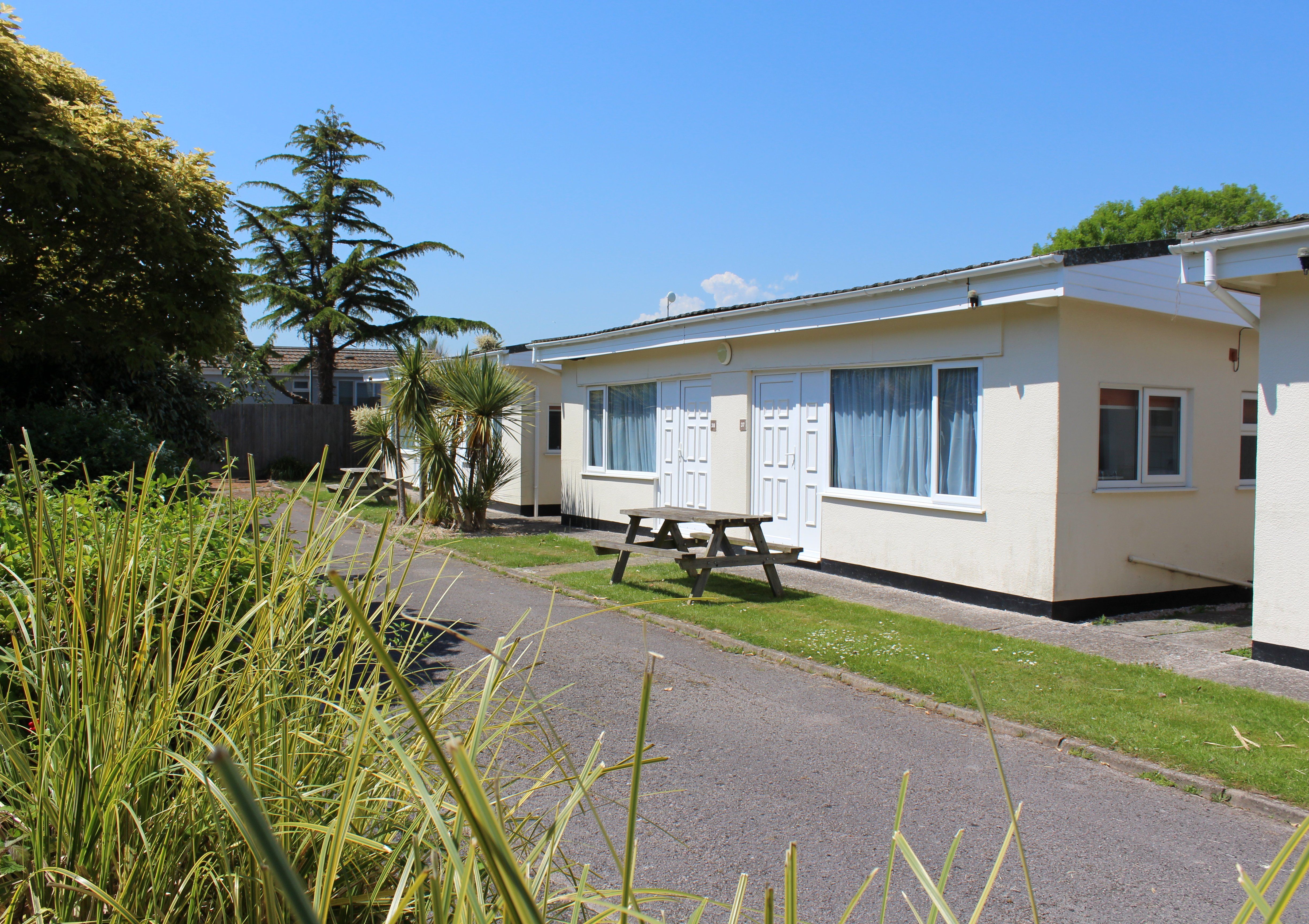 Exterior view of the Cedarwood Chalet at Hazelwood Holiday Park with a picnic table and landscaped gardens