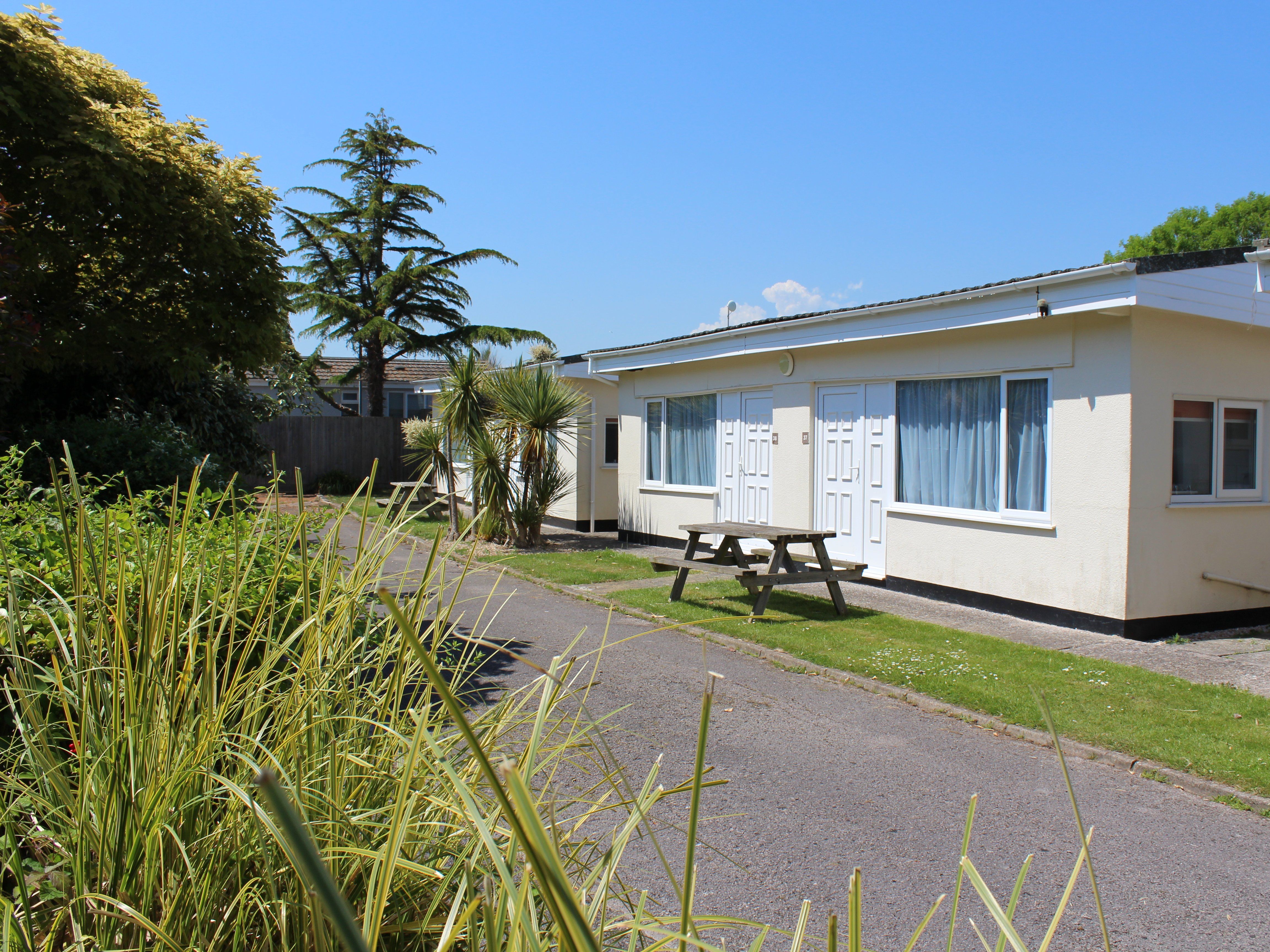 Exterior view of the Cedarwood Chalet at Hazelwood Holiday Park with a picnic table and landscaped gardens