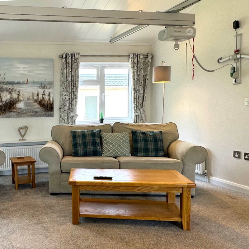 Bright living room with beige sofa, wooden coffee table and ceiling hoist rail