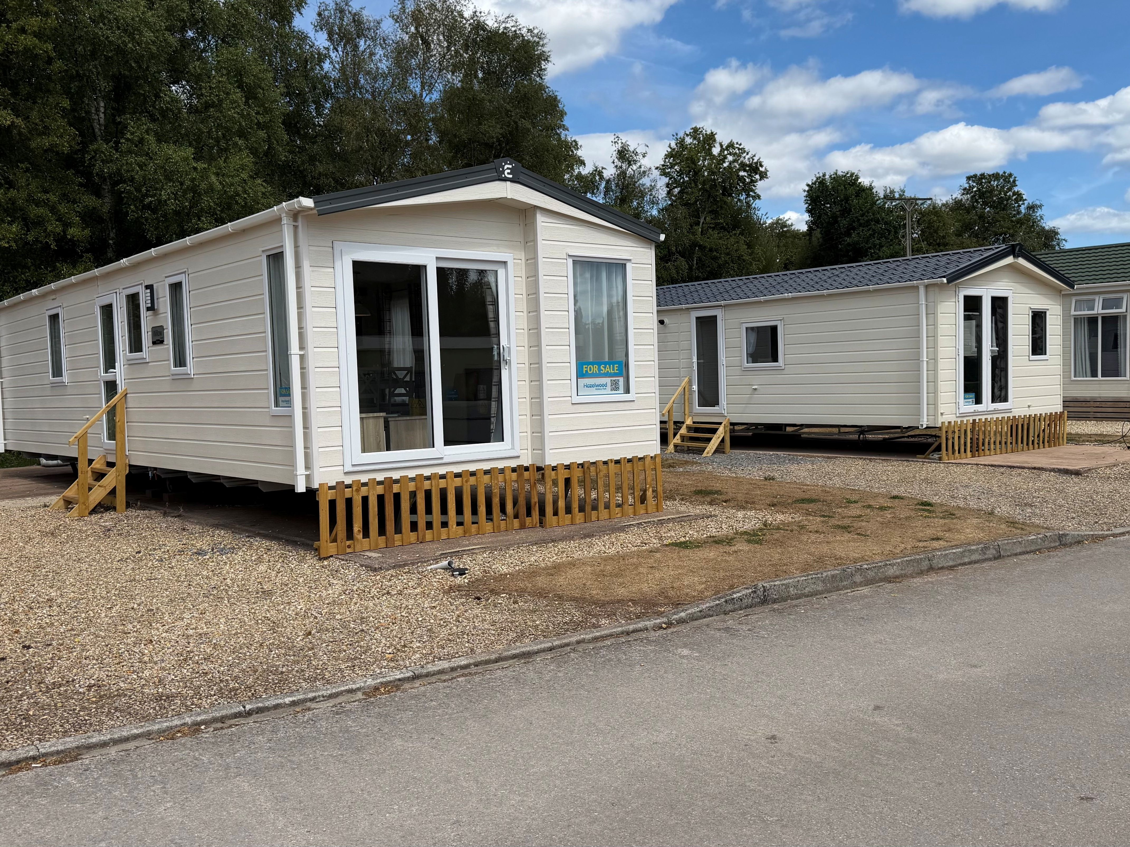 Three cream-coloured show homes on Riverside with decking and steps beside a road