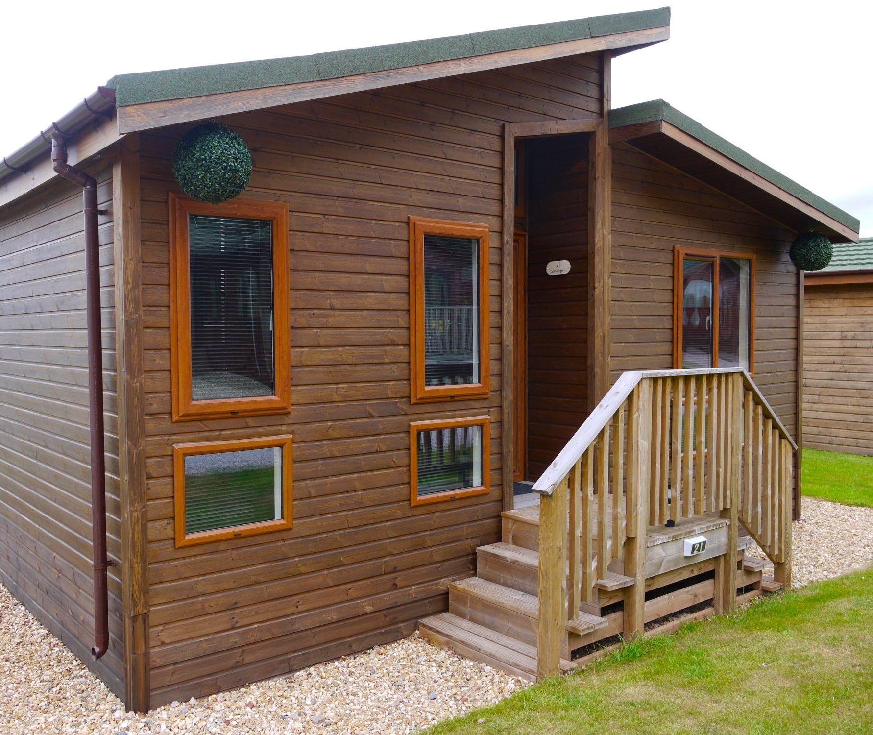 Timber lodge exterior with wooden steps, handrail and green pitched roof