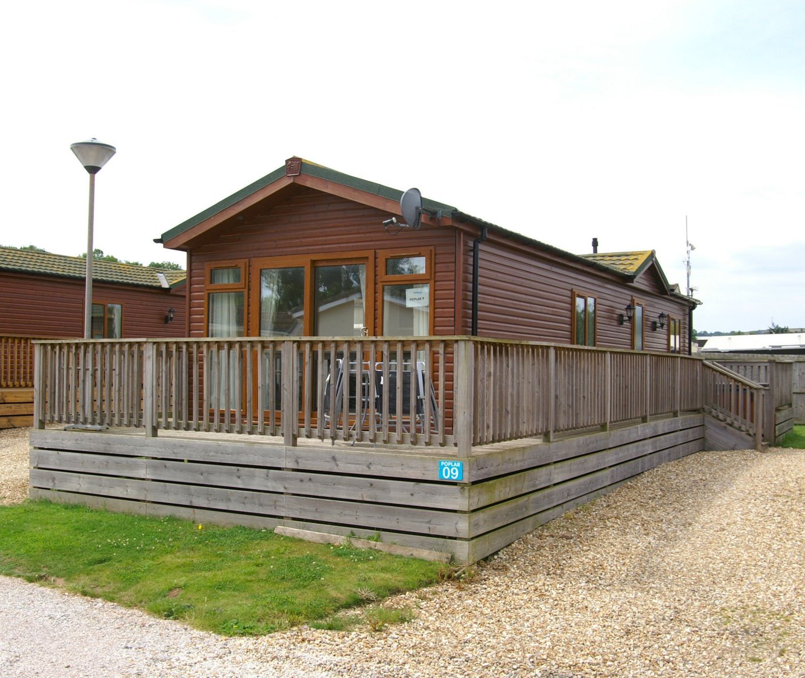 Exterior of a wooden holiday lodge with a large wraparound deck and ramp