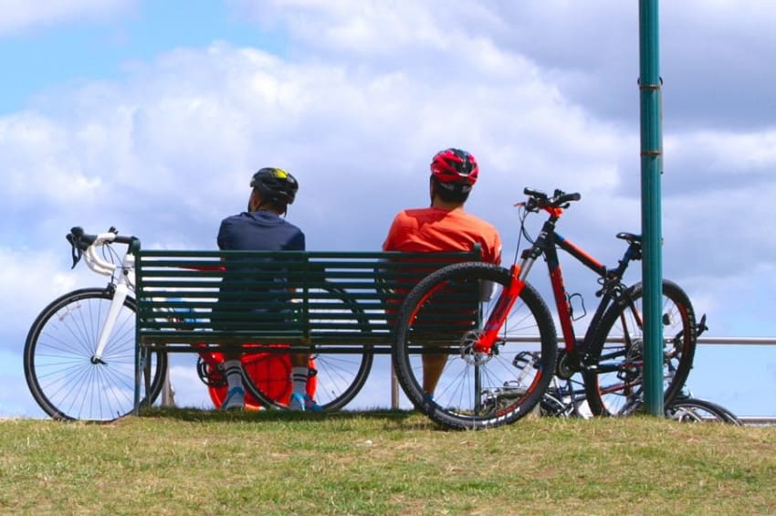 Two cyclists sitting on a bench