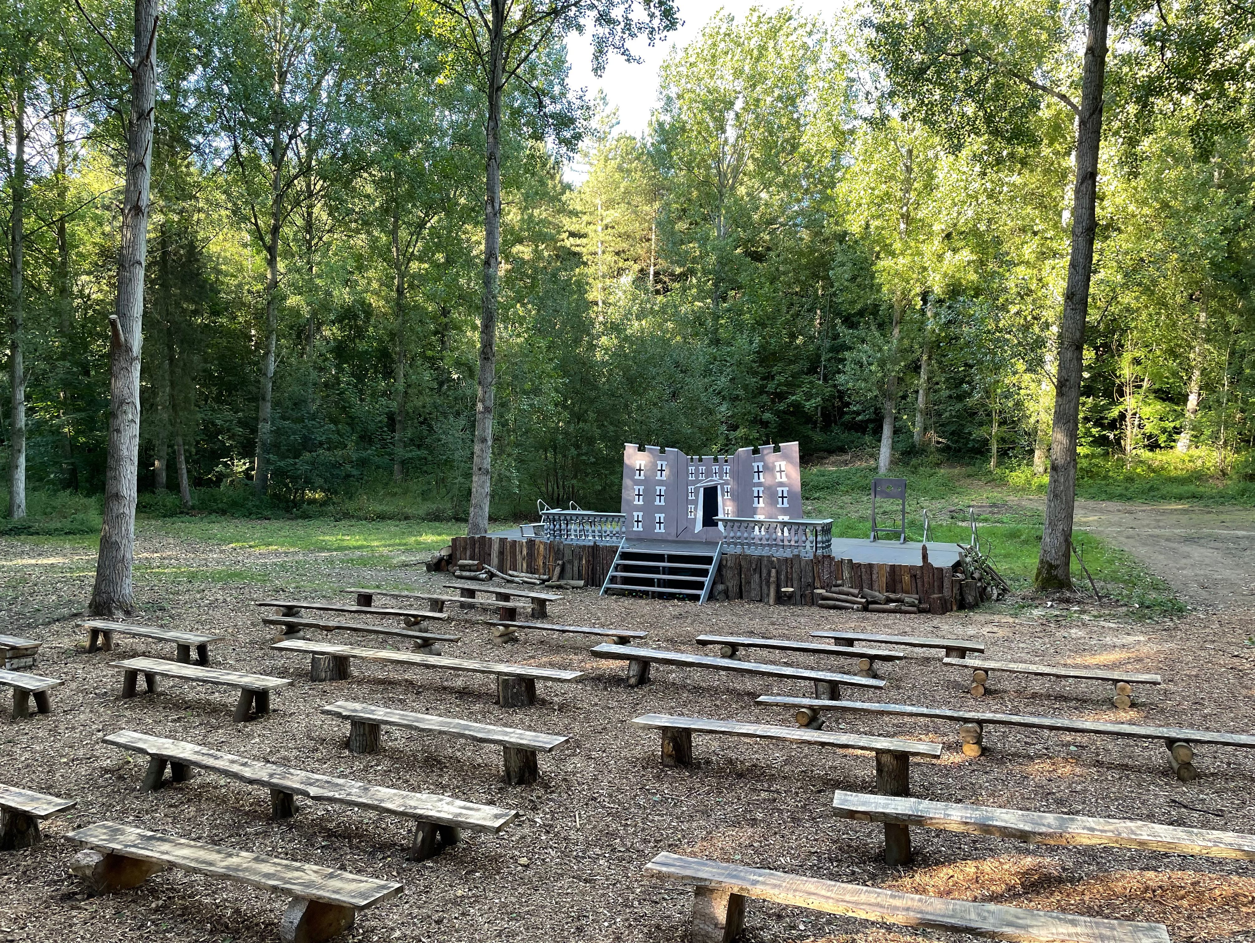 Outdoor wooden stage with benches surrounded by trees