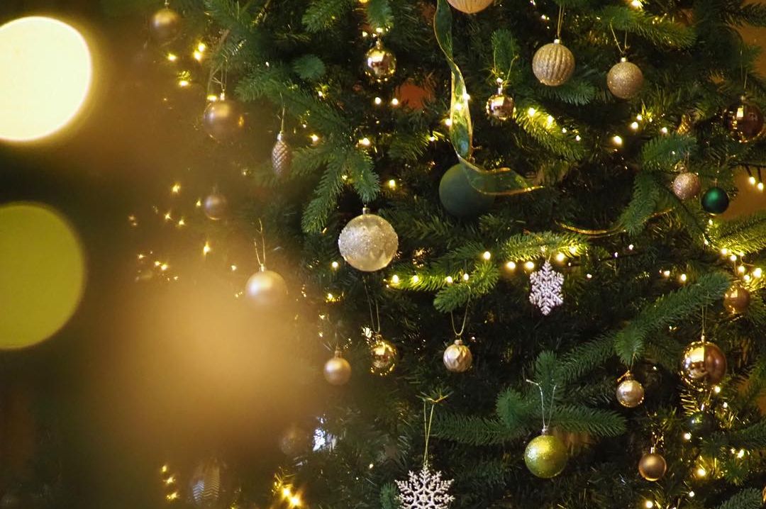 A decorated Christmas tree with ornaments and glowing lights next to striped chairs and a table.