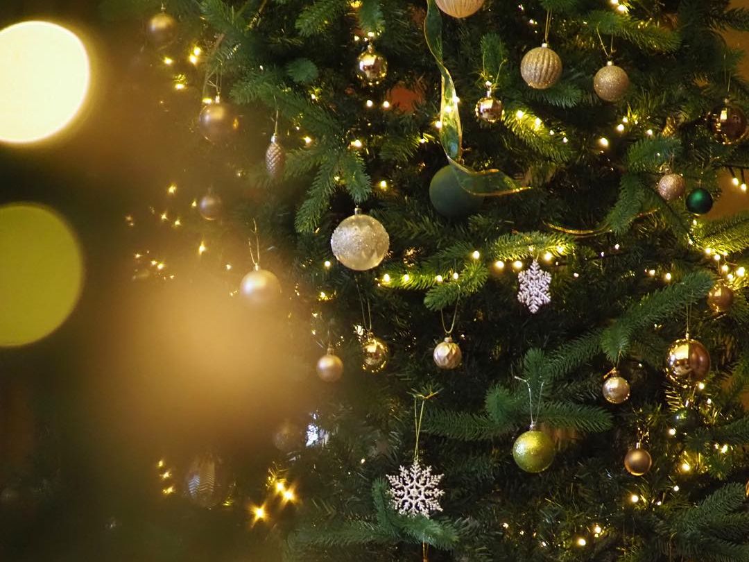 A decorated Christmas tree with ornaments and glowing lights next to striped chairs and a table.