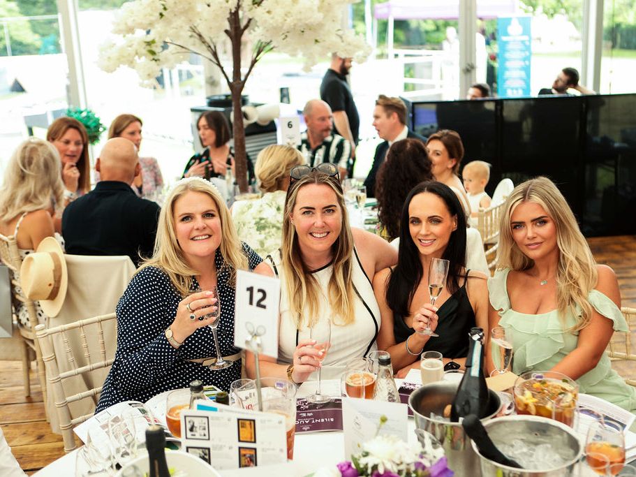 Group of women sitting at a table with drinks at a formal event