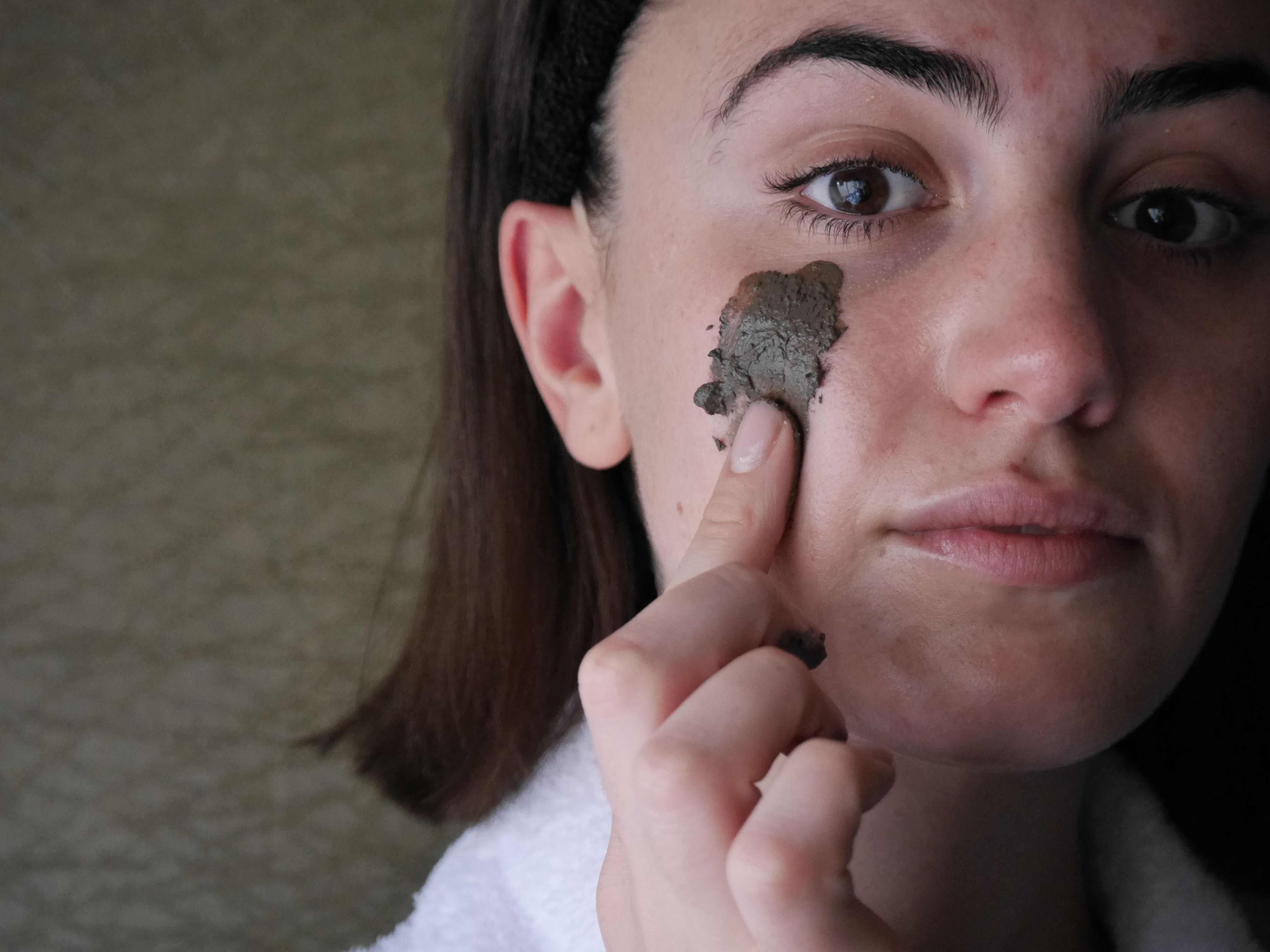 Person applying clay mask to face