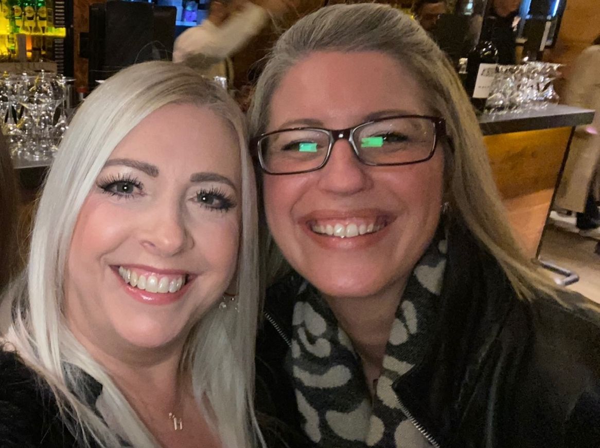 Two smiling women taking a selfie together in a bar or restaurant.