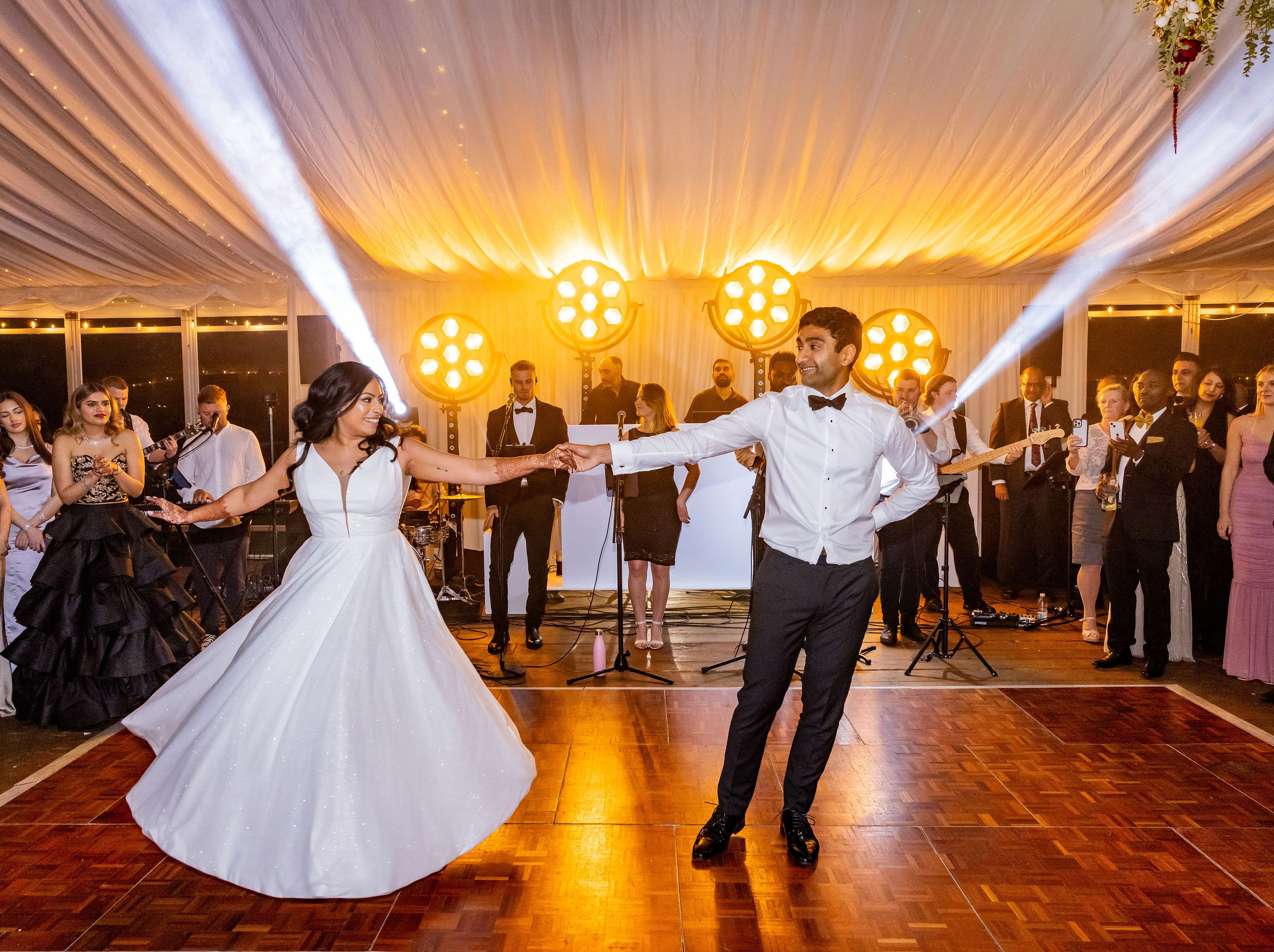 Bride and groom sharing their first dance at a wedding reception under a tent with guests watching.
