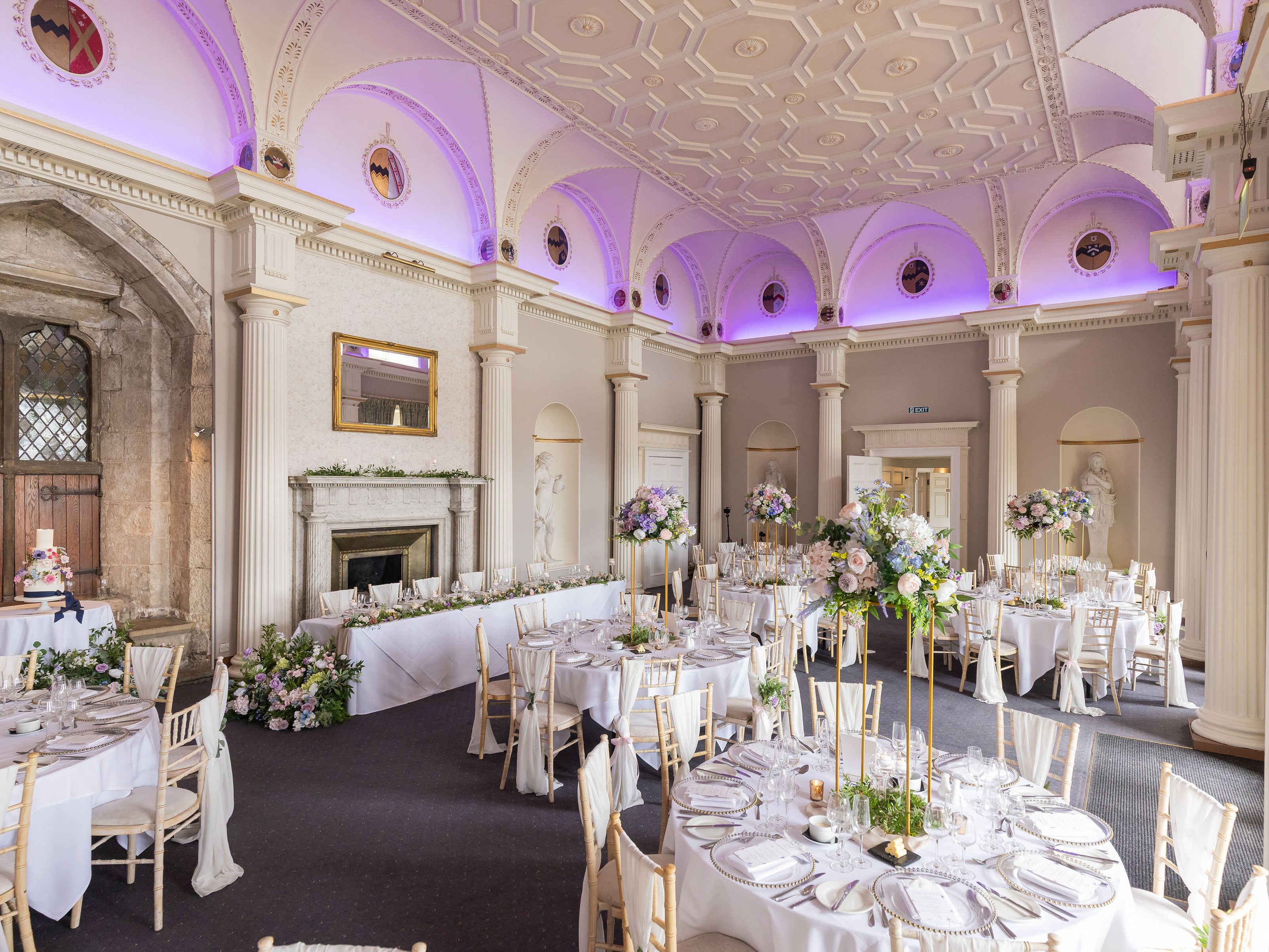 Elegant wedding reception hall with round tables, floral centerpieces, and classical architectural details