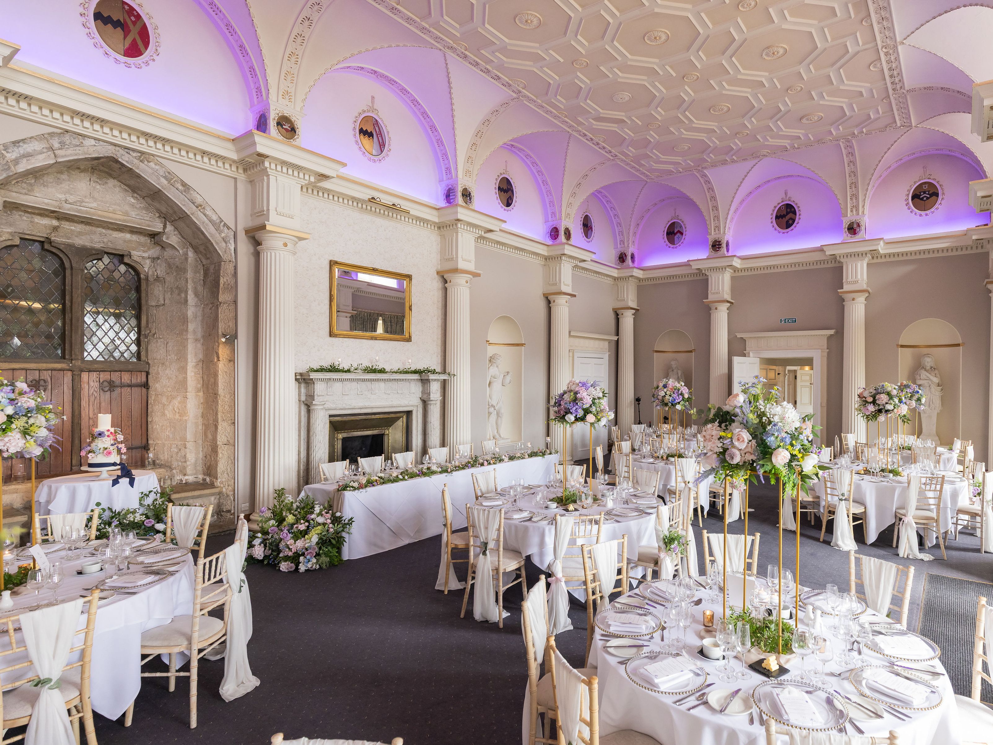 Elegant wedding reception hall with round tables, floral centerpieces, and classical architectural details