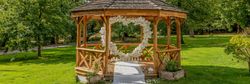 Wooden gazebo decorated with white flowers in a park on a sunny day