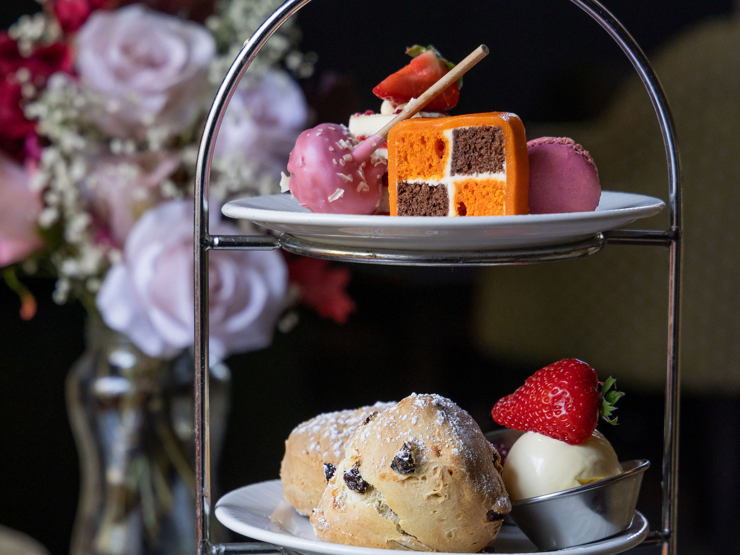 Three-tier afternoon tea stand with finger sandwiches, scones and assorted cakes