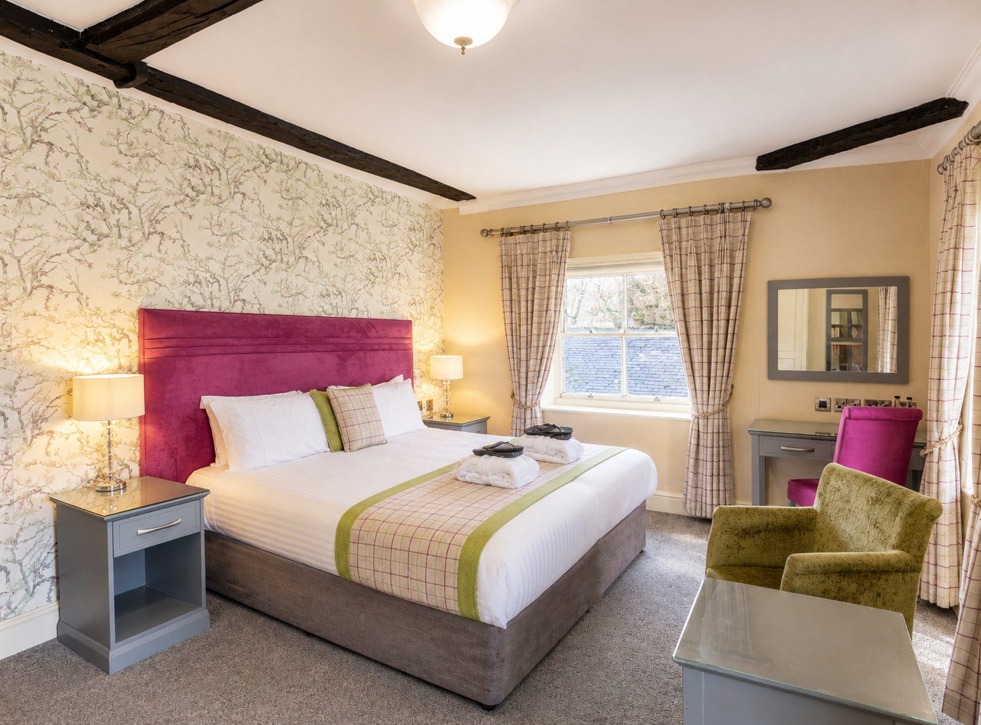 Cosy bedroom with a double bed, pink upholstered headboard, bedside lamps and a desk by the window