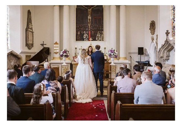 Bride and groom standing at the altar during a church wedding ceremony with guests seated in pews