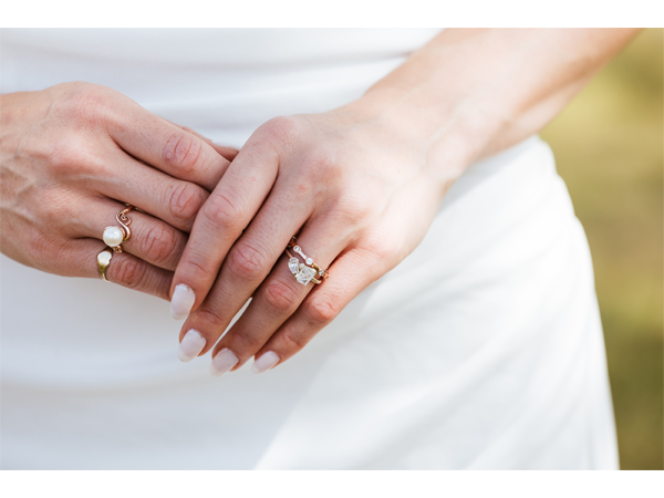 Close-up of hands with rings resting on a white dress