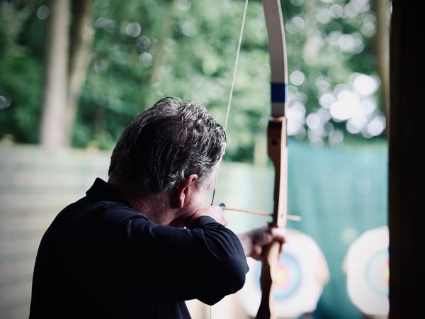 Man aiming a bow and arrow at archery targets outdoors