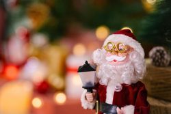 Santa Claus figurine holding a lantern with Christmas decorations in the background