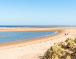 Sandy beach with grassy dunes and blue sky at the Norfolk Coast