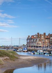 Scenic view of a coastal village with boats docked along the water and a historic hotel building in the background