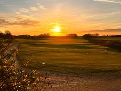 Golf course at sunset with golden sky and green fairways